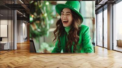 A Caucasian woman dressed in green for st Patrick's day laughing during video call Wall mural