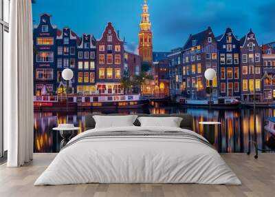 A tranquil night scene of Amsterdam, Netherlands, showcasing the historic canal houses with their reflections in the water. The scene includes illuminated windows and a church tower in the background. Wall mural