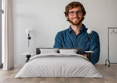 A happy, smiling young man with glasses and a beard. Wall mural