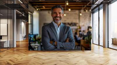 A smiling, middle-aged tech company CEO in a grey suit with arms crossed, standing inside an office. Wall mural