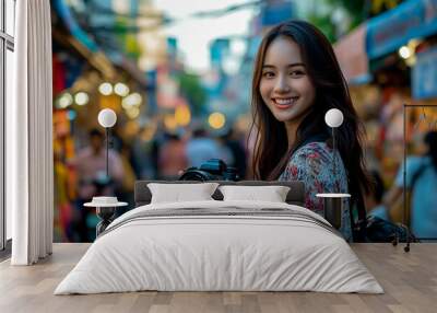 A woman tourist holding a camera and smiling while traveling. Wall mural