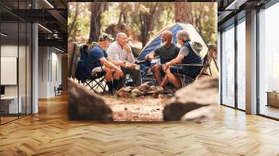 Senior people, camping and relaxing in nature for travel, adventure or summer vacation together on chairs by tent in forest. Group of elderly men talking, enjoying camp out conversation in the woods Wall mural