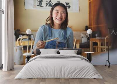 Japanese, food and woman at a restaurant eating for dinner or lunch meal using chopsticks and feeling happy with smile. Plate, date and person enjoy Asian cuisine, noodles or diet at a table Wall mural