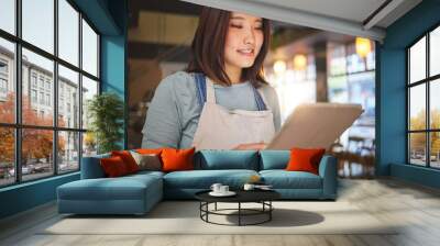 Restaurant, tablet and Asian woman online for order for food service, inventory and check menu. Coffee shop, small business and happy waitress, barista or manager on digital tech for cafe website Wall mural