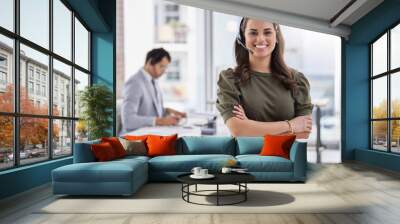 Delivering on excellent customer service. Portrait of a young call centre agent standing with her arms crossed in an office with her colleague in the background. Wall mural