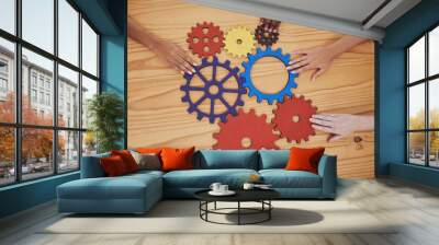 Hands, gears and collaboration with a team of people working with cogs and equipment on a table in the office. Teamwork, synergy and planning with a business group meeting to talk company strategy Wall mural