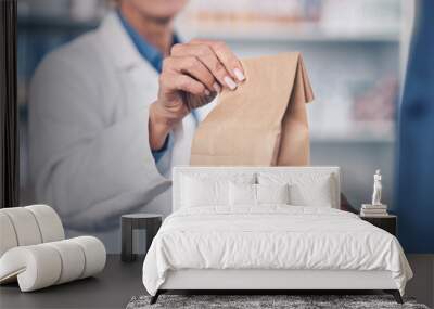 Woman, pharmacist and hands with medication for patient, healthcare or paper bag at the pharmacy. Closeup of female person or medical professional giving pills, drugs or pharmaceuticals to customer Wall mural