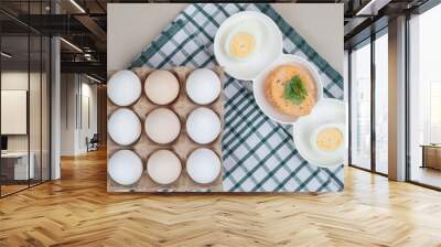 Fresh chicken white uncooked eggs with boiled egg on tablecloth Wall mural