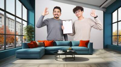 Two young men showing notebooks with pencils Wall mural