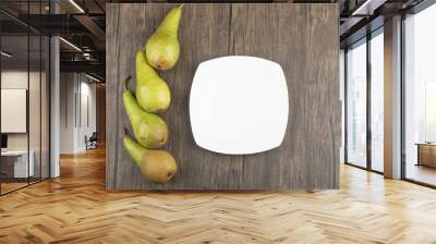 White plate and delicious ripe pears on wooden surface Wall mural