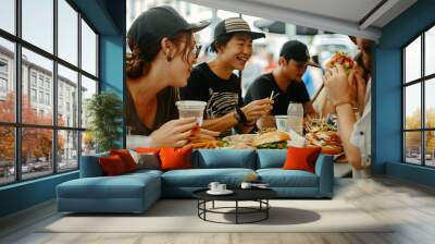 A group of people sitting around a table, enjoying a meal and trying out new foods together Wall mural