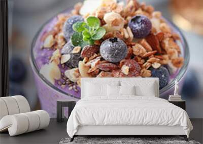 A glass of purple food with blueberries and nuts on top Wall mural