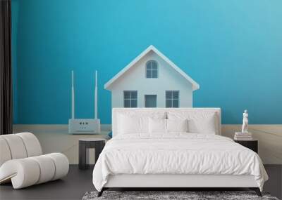 A white model home with a router and laptop in front of it on a wood table, blue background. Wall mural