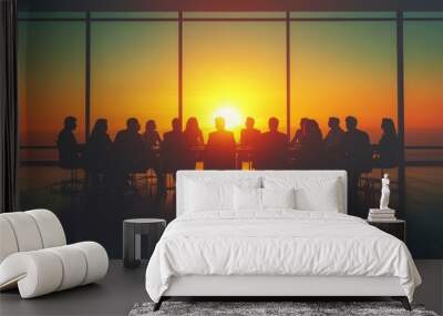 Silhouettes of business people sitting at a table in a conference room with a sunset view. Wall mural