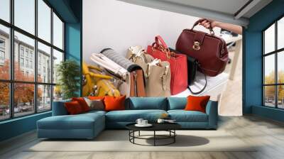 Woman taking her favourite handbag from collection of expensive fashinable bags standing on the shelf Wall mural