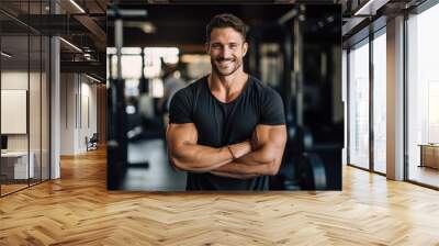 Smiling portrait of a young male caucasian fitness instructor trainer working in a gym Wall mural