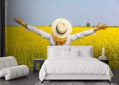 Happy woman in a field of yellow  rapeseed in bloom. Freedom and happiness concept. Wall mural