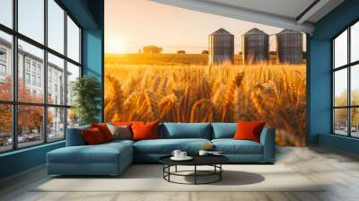 A field of golden wheat with three silo-like structures in the background Wall mural