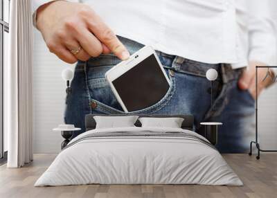 woman pushing big mobile phone in jeans pocket Wall mural