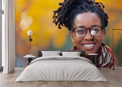 Portrait of black woman with glasses and smiling isolated on orange autumn bokeh background with copy sauce. Wall mural