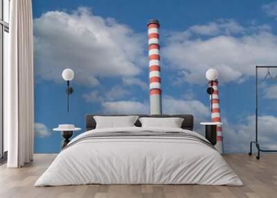 Close up of two factory chimneys with red and white stripes with a cloudy blue sky in the background Wall mural