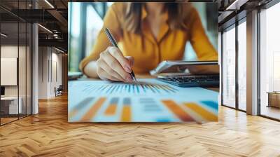 A person analyzing data with charts and graphs, using a pen and tablet in a modern workspace. Wall mural