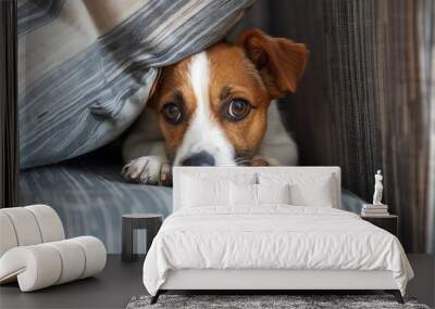 A small dog peeks out from behind a cushion, looking curious and playful. Wall mural