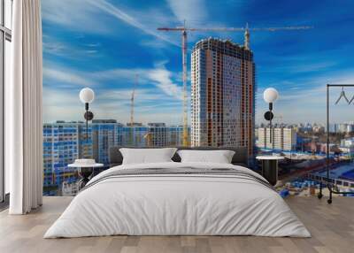 High-rise building under construction. The site with cranes against blue sky Wall mural