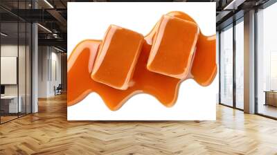 Two sweet caramel candies topped with caramel sauce on white background Wall mural