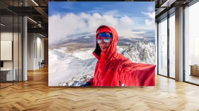 Selfi male mountaineer in snowy mountains, wearing a helmet with a backpack Wall mural