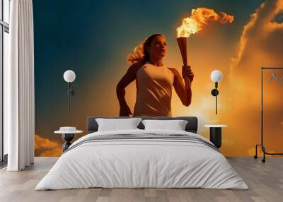 A female athlete runs with a torch, holding the Olympic flame against the sky. Wall mural