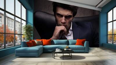 Portrait of a man sitting in a chair. Sinister look Wall mural