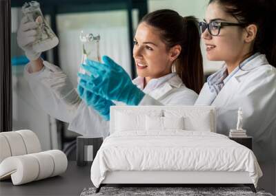  Two dedicated female lab scientists meticulously work together, focusing on agriculture genetic plants, applying their expertise to drive agricultural advancements. Wall mural