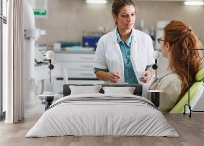 a professional female dentist, equipped with a bright smile, converses with her red hair female pati Wall mural