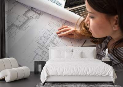 Female architect working at home.She looking at blueprint. Wall mural