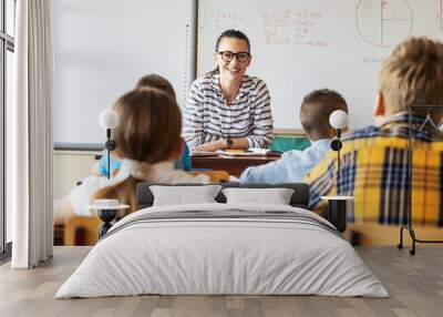 Female teacher lecture a new lesson to primary school kids in classroom. Wall mural