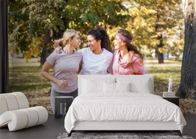 Group of female friends jogging at the city park.Relaxing after running and making fun.Autumn season. Wall mural