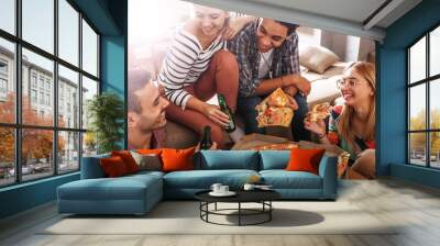 Group of friends making fun at the home party.They sitting in living room and eating pizza.	 Wall mural