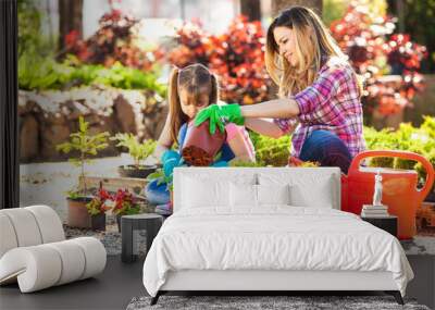 Mother and daughter planting flowers together. Wall mural