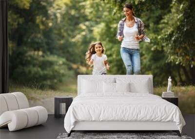 mother and daughter playing and running around the park on beautiful morning. Wall mural