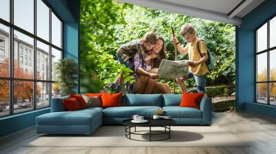 Mother and her little sons hiking .They taking a break and sitting on the old stairs.Examining map. Wall mural