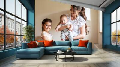 Mother playing with her daughter and baby boy in living room.	
 Wall mural