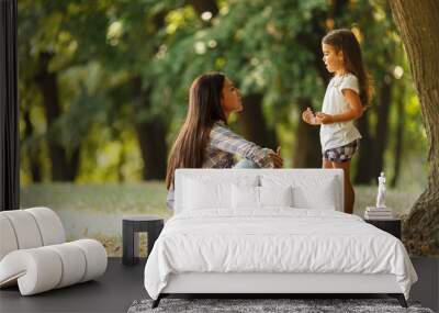 Mother sitting with her daughter and playing around the park on a beautiful morning.	  Wall mural