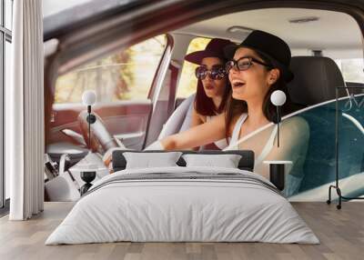 Two young women on car trip.They are driving the car and making fun.Positive emotions. Wall mural