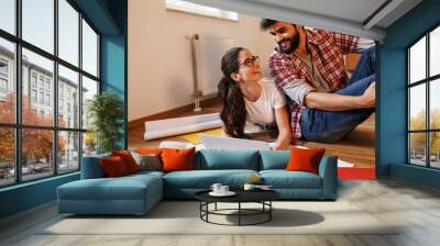 Young couple moving into a new house.They sitting on floor and calculate savings and home budget. Wall mural