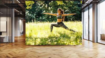 Young female stretching and relaxing after jogging outdoor. She contemplates in yoga warrior pose Wall mural