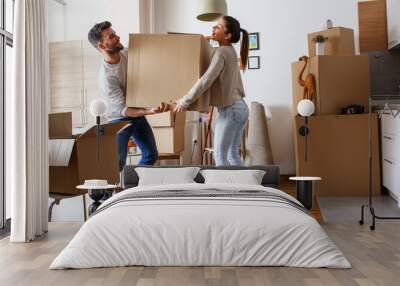 Young married couple carrying big cardboard box into new home. Moving house.	 Wall mural