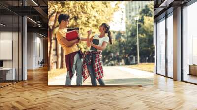 Young student couple going to college lecture. They walk through university campus and laughing. Autumn.	 Wall mural