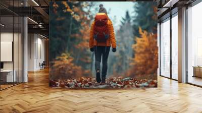 Woman with backpack walks through autumn foliage forest woods, colorful red and yellow leaves of trees create beautiful landscape, outdoor hike activities and weekend adventures, back view Wall mural