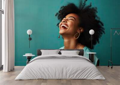 A joyful black woman with her mouth wide open in laughter, expressing pure happiness. Wall mural